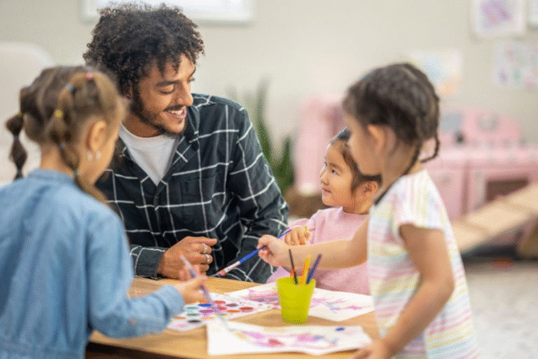 A man helps small children paint
